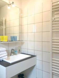 ein weißes Badezimmer mit einem Waschbecken und einem Spiegel in der Unterkunft Lille Hüs in Westerland