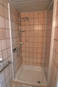 eine Dusche im gefliesten Bad mit Badewanne in der Unterkunft Eva in Westerland