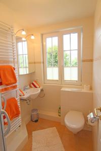 ein Bad mit einem WC, einem Waschbecken und Fenstern in der Unterkunft Sünje in Westerland