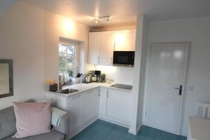 a kitchen with white cabinets and a sink and a couch at Nelle 1 Stock in Wenningstedt