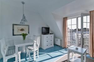a white dining room with a white table and chairs at Nelle 1 Stock in Wenningstedt