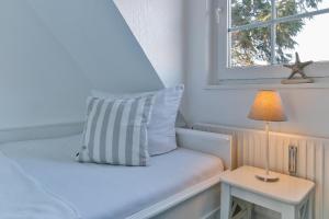 a bed with a pillow and a table with a lamp at Nelle 1 Stock in Wenningstedt