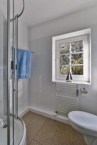 a white bathroom with a toilet and a window at Nelle 1 Stock in Wenningstedt +5 photos