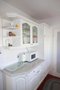 una cocina con armarios blancos y microondas en una encimera en Pesel im Friesenhaus Sieben-Linden ebenerdig en Archsum
