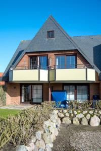 een stenen huis met een balkon en een tuin bij Sylt Liebe in Wenningstedt