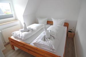2 bedden in een kamer met witte lakens en kussens bij Osten in Westerland