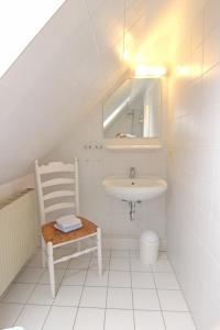 ein Badezimmer mit einem Waschbecken, einem Stuhl und einem Spiegel in der Unterkunft Christine - Munkmarsch in Munkmarsch
