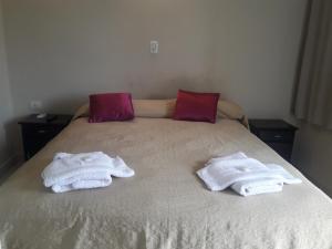 duas toalhas sentadas numa cama com duas mesas de cabeceira em Apart Termal Centro em Termas de Rio Hondo