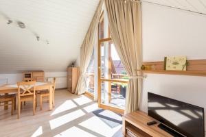 a living room with a dining table and a television at Ferienwohnung Lauser Dg in Herdwangen-Schönach