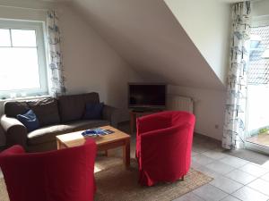 ein Wohnzimmer mit einem Sofa und roten Stühlen in der Unterkunft Darsser Weg in Zingst