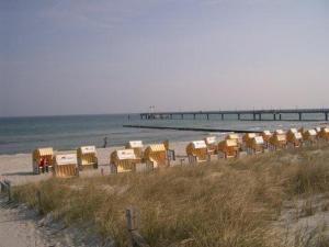 - une rangée de chaises sur une plage avec une jetée dans l'établissement Darsser Weg, à Zingst
