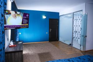 Habitación con TV y pared azul. en Evim Otel, en Zaqatala