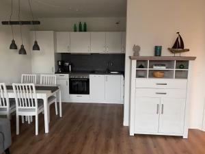 - une cuisine avec des placards blancs, une table et des chaises dans l'établissement _Kiek mal_Kiek_, à Zingst