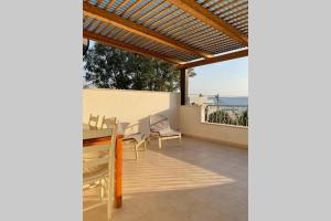 un patio con pérgola de madera, mesa y sillas en Villa Sarah in Galilee - All Nations Inn, en Poriyya