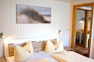 1 dormitorio con 1 cama con almohadas blancas y una foto en Haegerende _Alte Liebe_, en Groß Kirr
