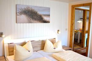 a bedroom with a bed with white pillows and a picture at Haegerende _Alte Liebe_ in Groß Kirr
