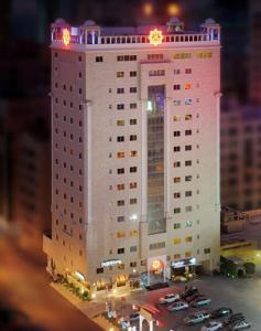 a large white building with cars parked in a parking lot at Al Safir Tower - Residence in Juffair