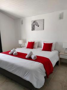 um quarto com uma grande cama branca com almofadas vermelhas em Casa Areias Boutique Apartments em Albufeira