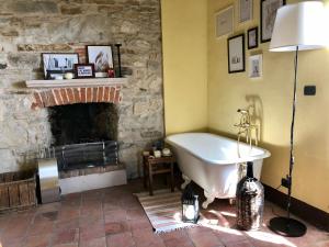 a bath tub in a room with a stone fireplace at Cascina Bertolotto Wine Resort in Spigno Monferrato