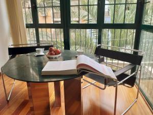 - une table avec un livre ouvert et un bol de fruits dans l'établissement LARGE Apartment with large and sunny Terrace - Garden & Outdoor Gym , ALICANTE CENTER, à Alicante