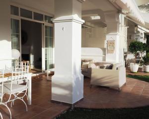 un porche con una columna blanca, sillas y una mesa en Marbella Holiday & Golf Garden Apartment, en Marbella
