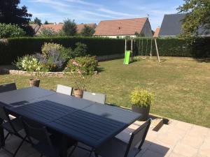 a blue table and chairs in a yard with a swing at Gîte Le Chantecaille in Mer