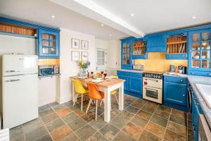 cocina con armarios azules, mesa y sillas en Abigail's Cottage Air Manage Suffolk en Woodbridge