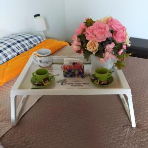 Una mesa de café blanca con flores y tazas. en Il colle degli ulivi en San Calogero