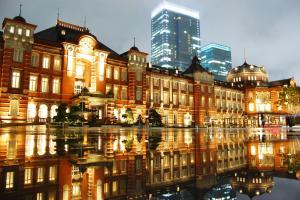 a large building with a reflection in the water at Smile Hotel Tokyo Nihonbashi in Tokyo