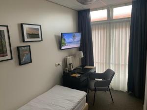 een hotelkamer met een bureau, een bed en een computer bij Sevenster Delden in Delden