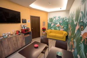 a waiting room with a yellow couch and a tv at Hostal La Carretera in Torrejón de Ardoz