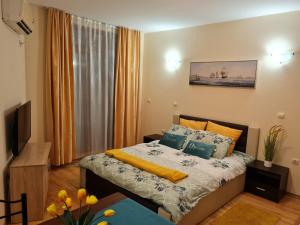 a small bedroom with a bed and a television at Апартаменти-Студия в Комплекс Нестинарка in Tsarevo