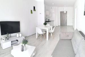 a white living room with a couch and a table at Green Apartment Promenada Gwiazd- widok na morze. in Międzyzdroje
