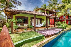 a house with a wooden deck next to a swimming pool at Domus Villas in Pipa