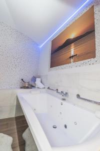 a white bath tub in a bathroom with a tv on the wall at Hostal La Carretera in Torrejón de Ardoz