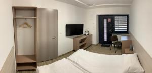 um pequeno quarto com uma cama e uma televisão em Ludowa Restauracja & Noclegi em Kietrz