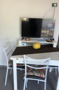 uma secretária com uma televisão e uma mesa com 2 cadeiras em La Pedrosa 83 em Scalea