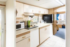 una cucina con mobili bianchi e un forno a microonde di Mobilheim Stella - Výrovická přehrada a Výrovice Altre 7 foto