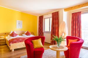 a bedroom with a bed and two chairs at Das Moser - Hotel Garni am See (Adults Only) in Egg am Faaker See