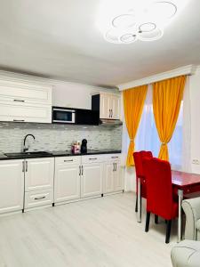 una cucina con armadi bianchi, tavolo e sedie rosse di Apartament Premium Isabella a Arad