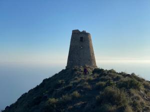 una persona parada en la cima de una colina con un faro en Hostal Puerto Genovés en San José