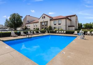 a swimming pool with chairs and a house in the background at Red Roof Inn Murfreesboro in Murfreesboro