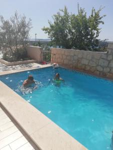 two people are swimming in a swimming pool at Apartment Sunset in Šibenik