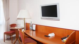 Habitación con mesa y TV en la pared. en Carmina am See, en Karnin