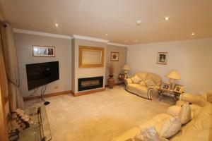 a living room with couches and a flat screen tv at Woodlands Guest Accomadation in Oughterard