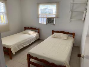 two beds in a room with white walls and windows at "Casa Viña Del Mar" Playa Blanca in San Antero