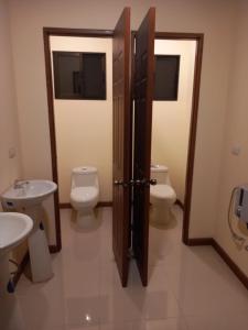 ein Badezimmer mit 2 WCs, einer Tür und einem Waschbecken in der Unterkunft Hostel Nicoa in Nosara
