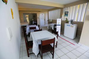 uma sala de jantar com mesas e cadeiras e uma cozinha em Pousada Sossego Suítes em Porto de Galinhas