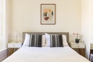een slaapkamer met een wit bed met gestreepte kussens bij Contemporary 1 Bedroom Bloomsbury Apartment in Londen