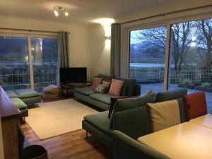 a living room with green couches and a large window at Snowdonia Mawddach escape in Dolgellau